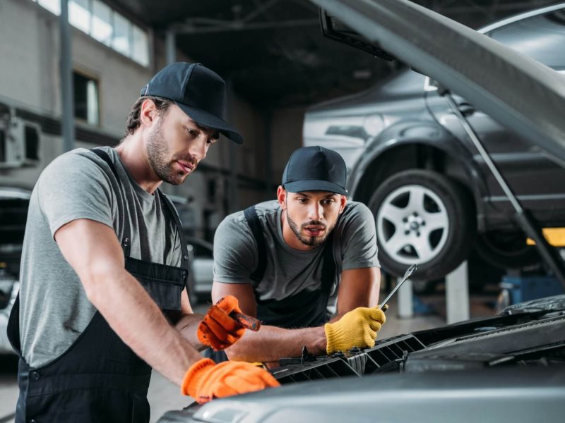 professional-manual-workers-repairing-car-in-mechanic-shop